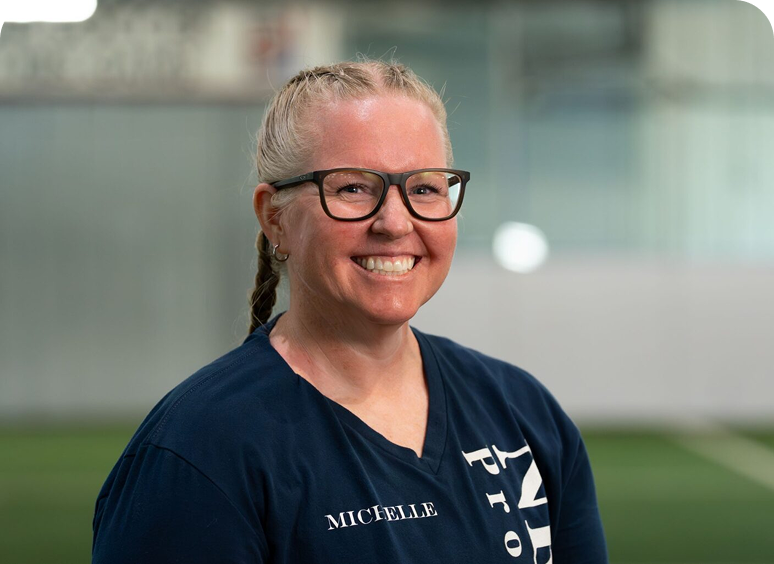 Smiling person with glasses in sports setting.