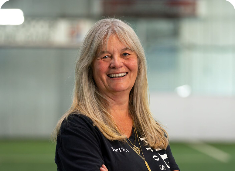 Smiling woman with long gray hair indoors.