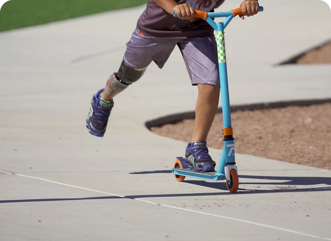 Child riding a scooter on sidewalk.